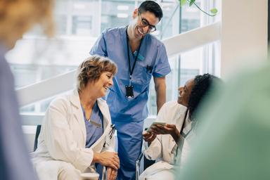 Två läkare i vita rockar pratar med en sjukskötare i blåa kläder.